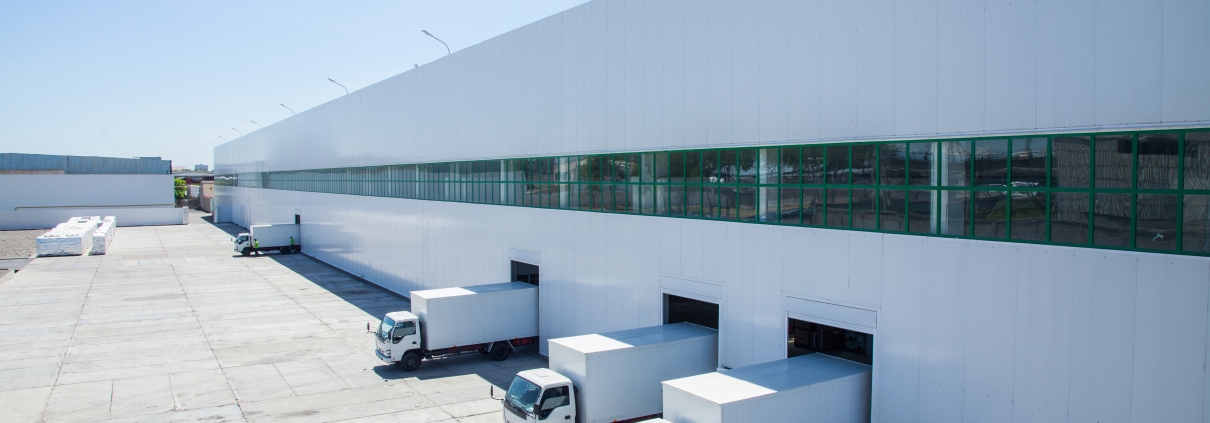 Modern warehouse with multiple loading dock doors and trucks parked outside for freight shipping